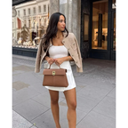 Beige tweed cropped jacket with gold buttons and patch pockets, worn over a white dress