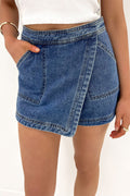 Blue faux-wrapped denim mini skort with front patch pockets and crossover hem