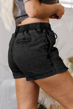 Black denim shorts with elastic waist and drawstring, back pockets visible.