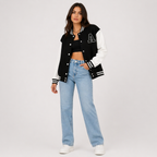 Black varsity bomber jacket with white contrast sleeves, snap buttons, striped rib trim