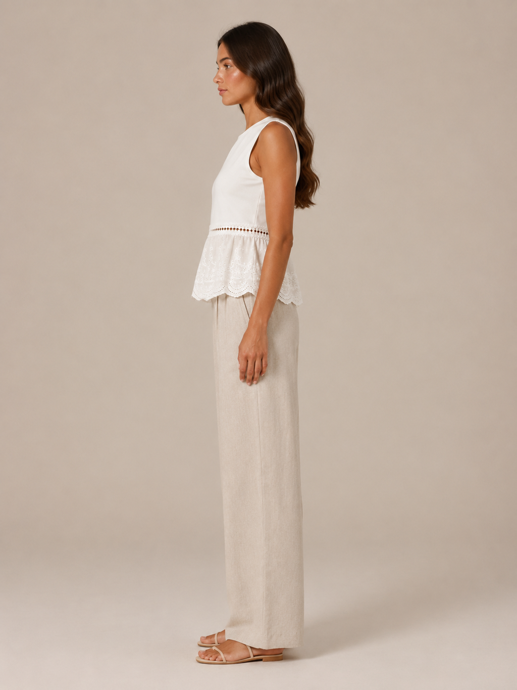 Women's white peplum tank top with lace trim and beige wide-leg linen pants, side view