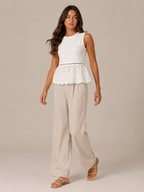 Women's white peplum tank top with lace hem and beige wide-leg linen pants
