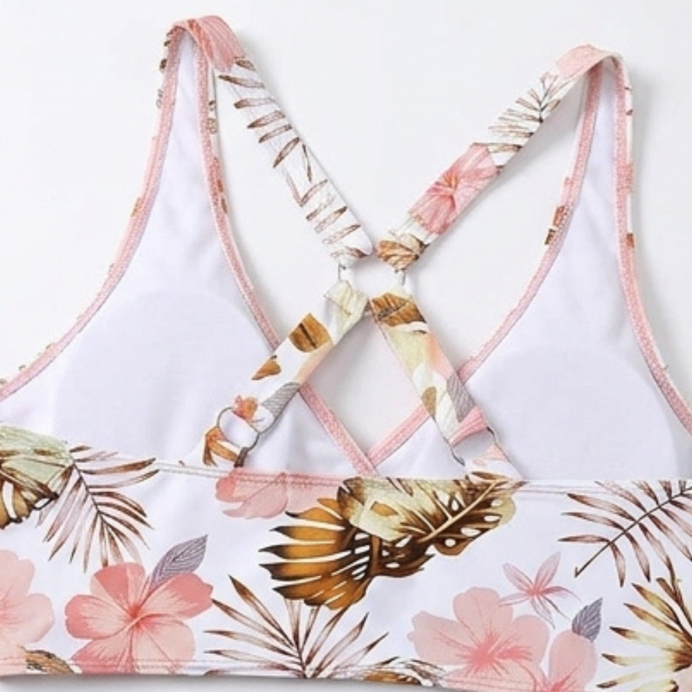 Floral bikini top with crisscross tie straps and pink trim on white base