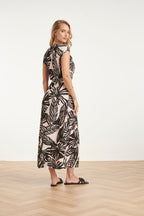 Women's black maxi dress with off-white leaf print, back view with gathered waist tie