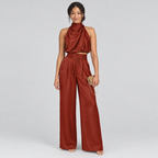 Rust-red satin halter top and wide-leg trousers co-ord with gold clutch