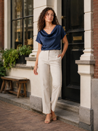 Navy draped-neck blouse with short sleeves, worn with light trousers