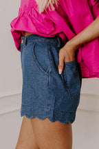 High-waist blue denim shorts with scalloped hem and back patch pocket detail