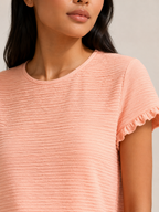 Close-up of soft apricot textured relief-structure short-sleeve crewneck top