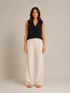 Black sleeveless V-neck blouse with pleat detail and draped wrap front