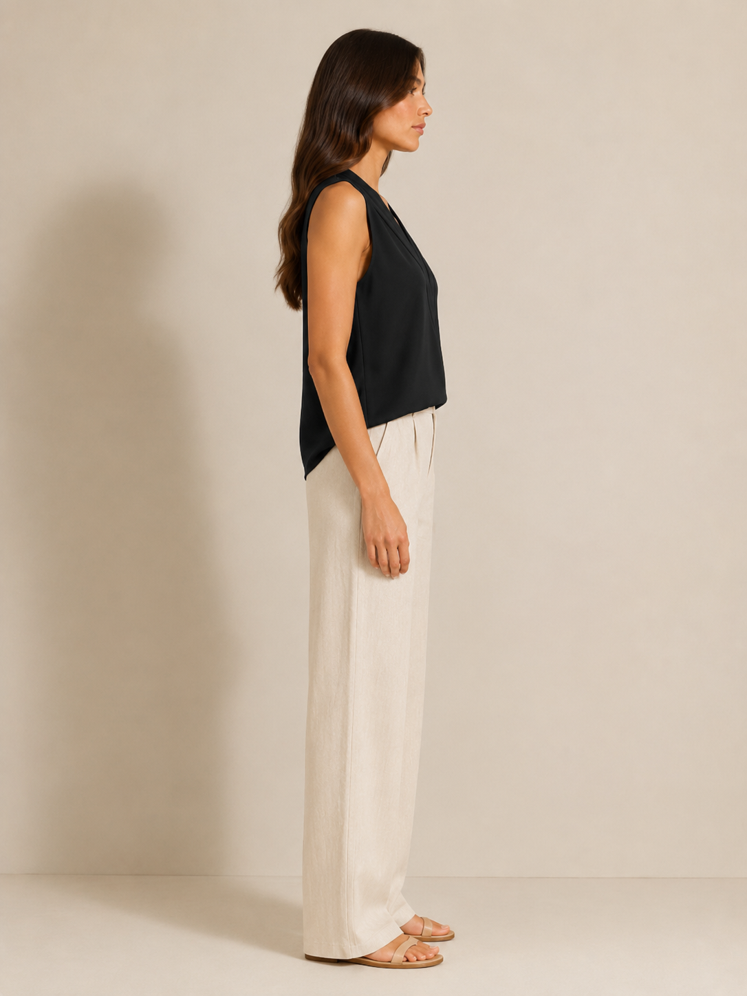 Black sleeveless V-neck blouse with pleat detail, side profile