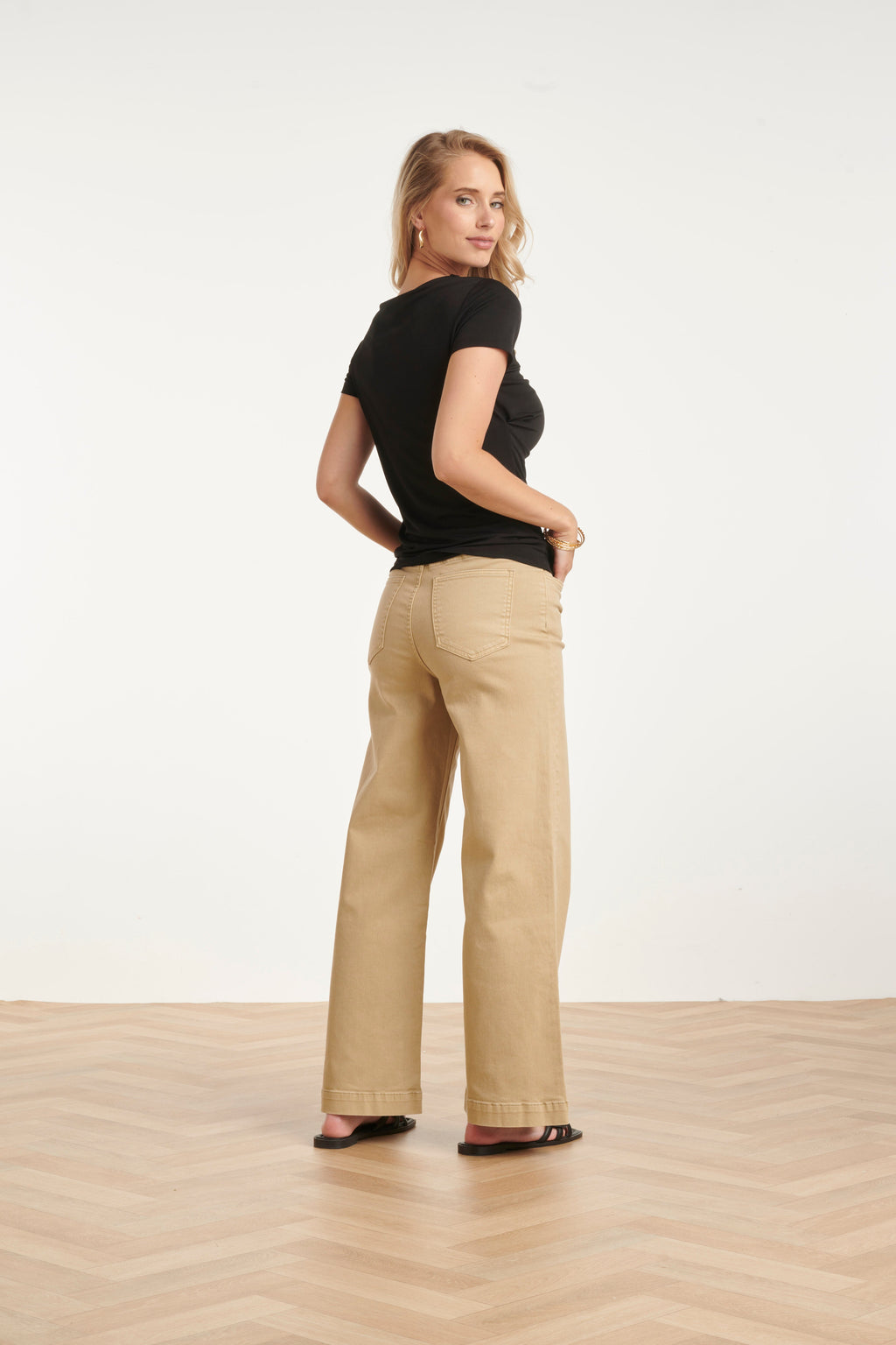 Black back-view blouse with short sleeves, draped asymmetrical neckline detail.