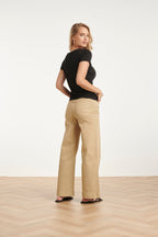 Black back-view blouse with short sleeves, draped asymmetrical neckline detail.