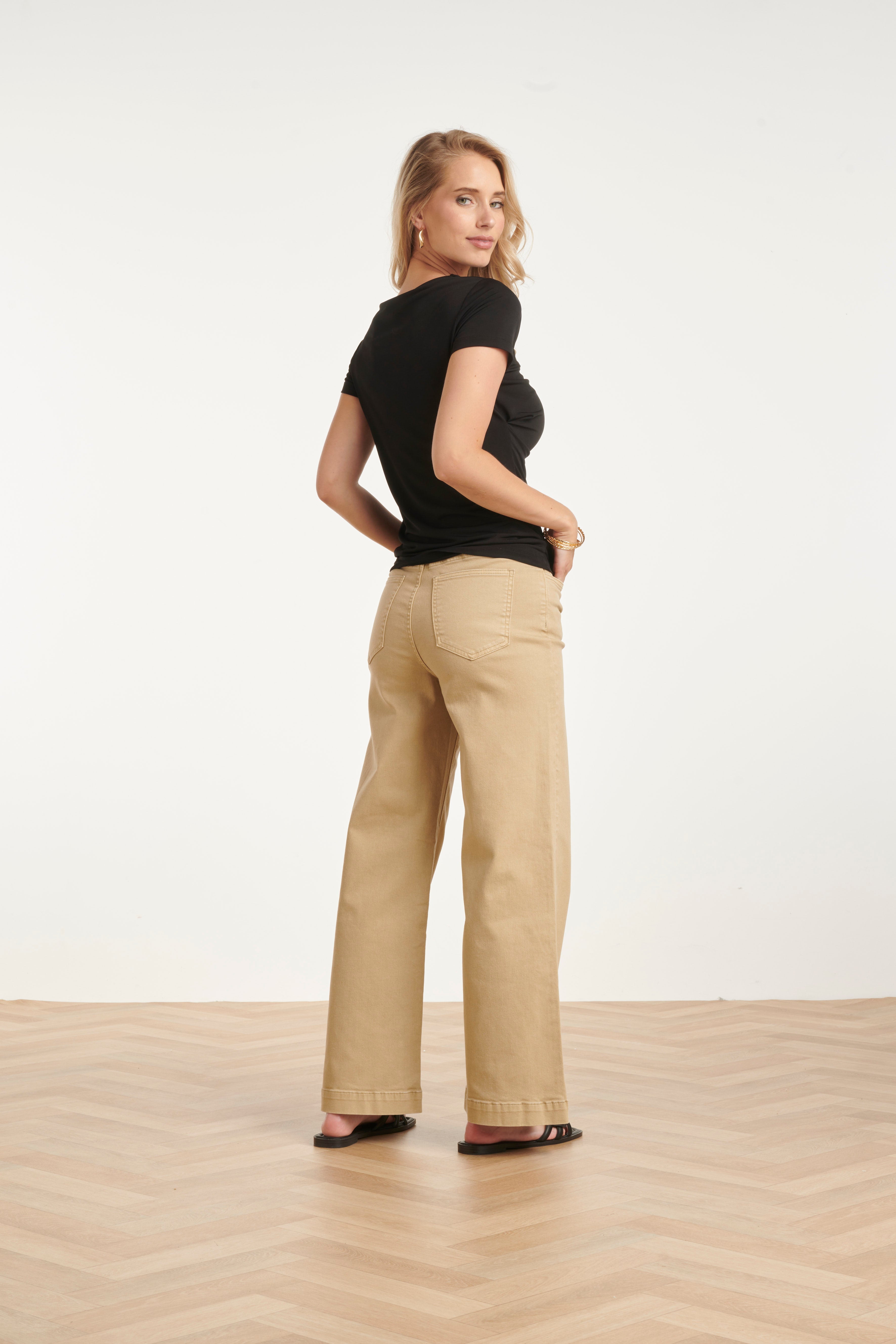 Black back-view blouse with short sleeves, draped asymmetrical neckline detail.
