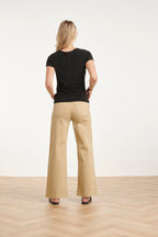 Black short-sleeve blouse back with draped asymmetrical neckline detail.