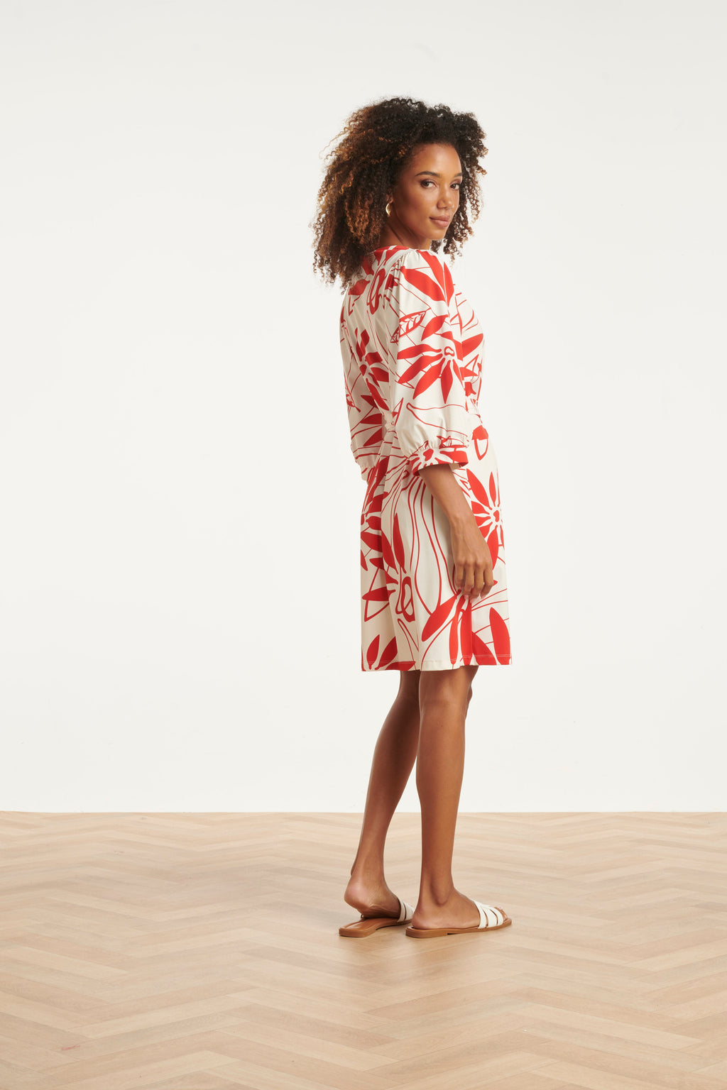 White dress with red floral print, side view with tie waist and three-quarter sleeves