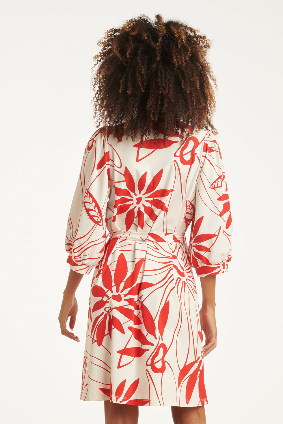 Back view of white dress with red floral print and tie waist, three-quarter sleeves