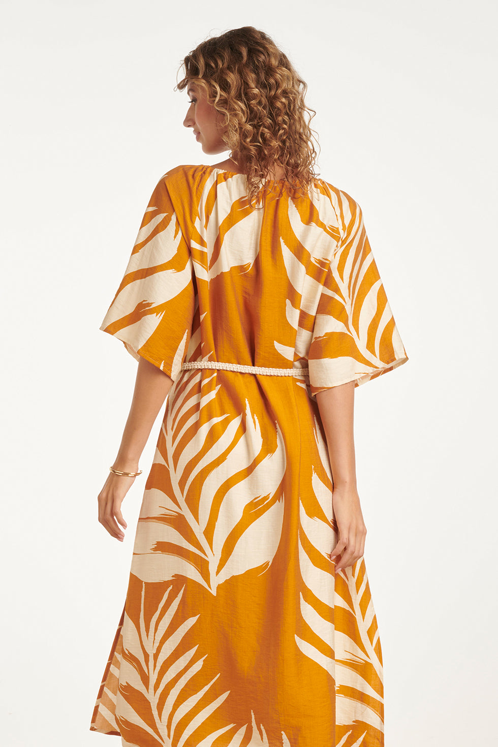 Mustard tunic dress with off-white leaf print, side view showing tied waist