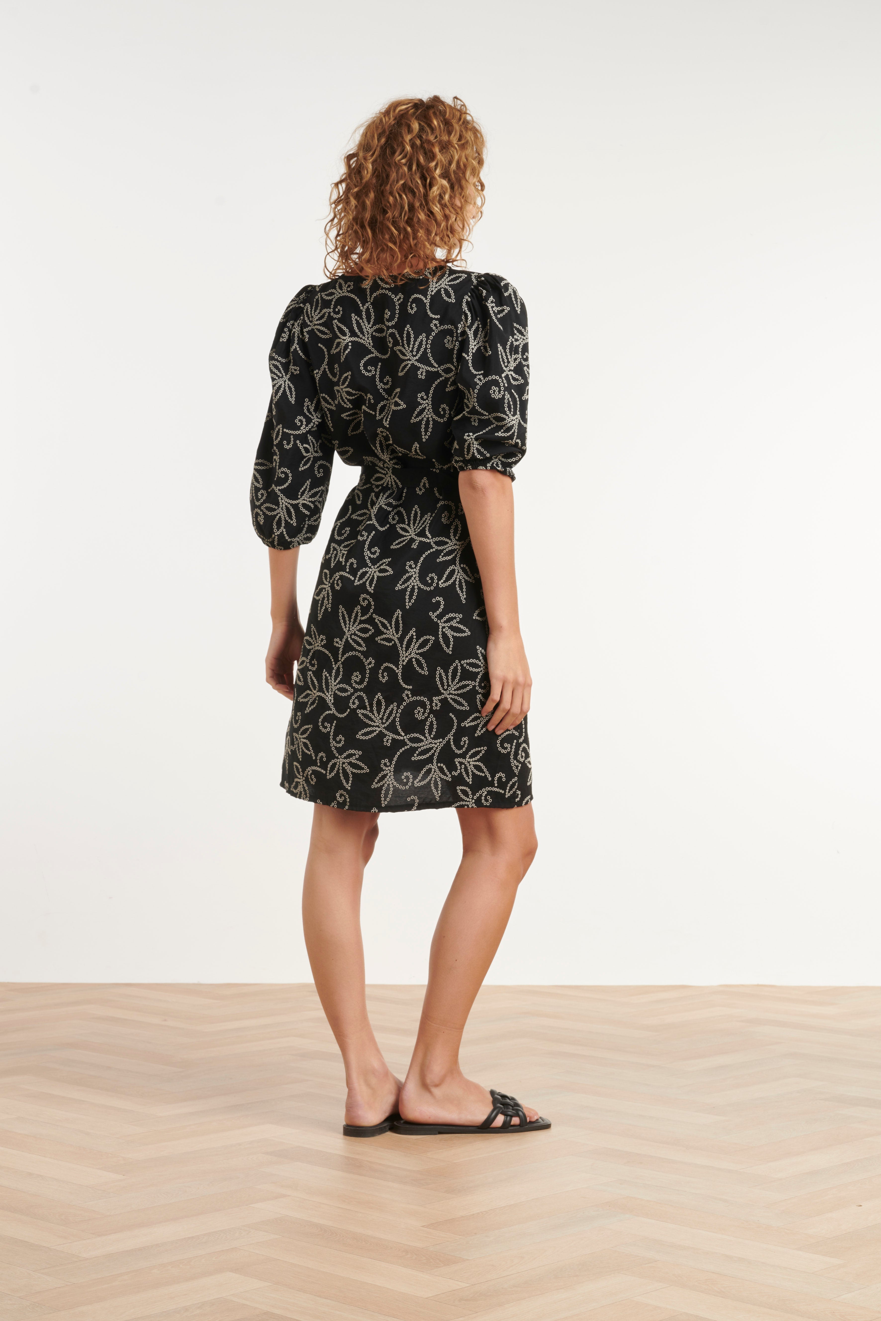 Black V-neck floral dress with waist belt and puff sleeves, above-knee length (back view)