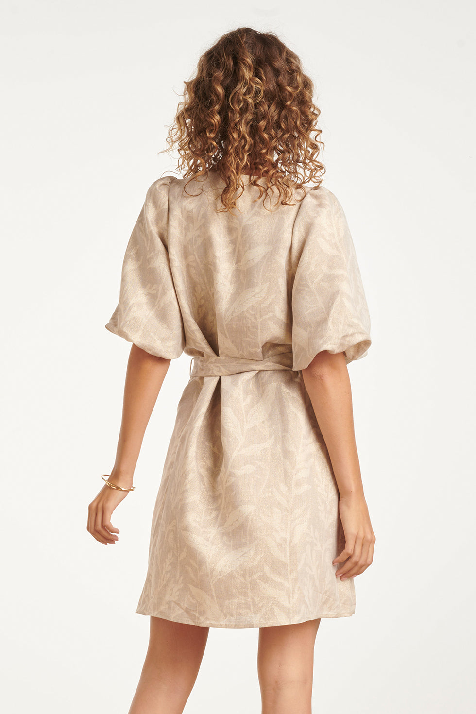 Back view of leaf-print mini dress with gathered puff sleeves and tied waist.
