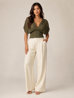 Emerald green V-neck draped blouse with puff sleeves and ruched wrap front