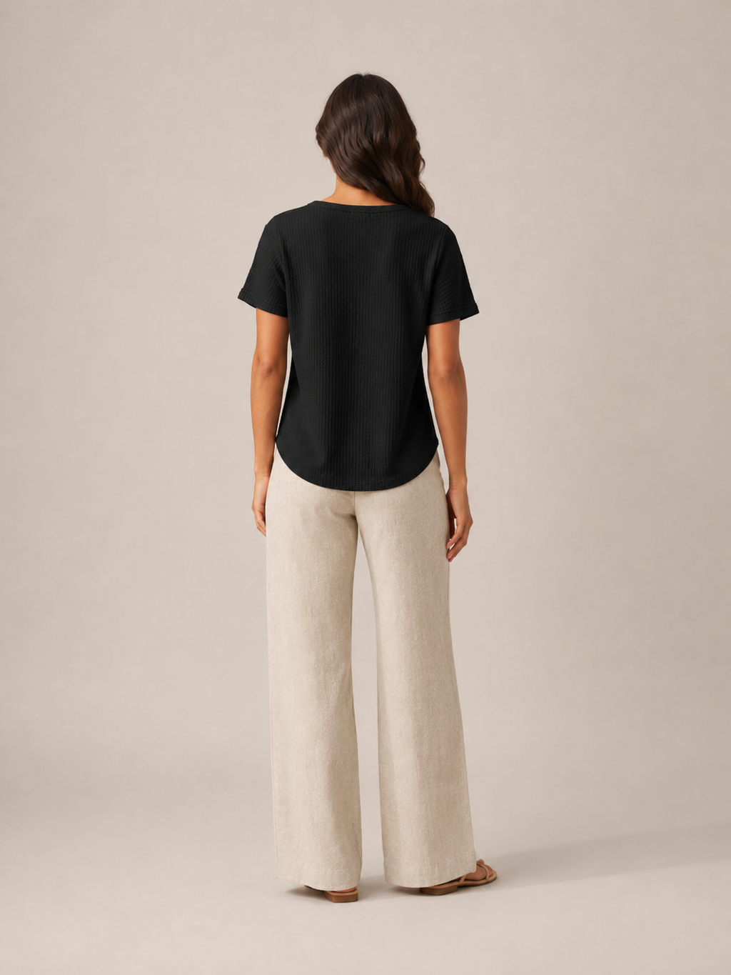 Women’s black short-sleeve button henley top from back view with curved hem