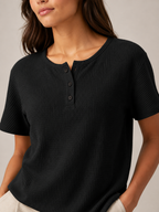 Close-up of women’s black short-sleeve button henley top neckline with small dark buttons