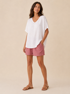 Women’s loose V-neck white top with short wide sleeves and relaxed, flowing fit.