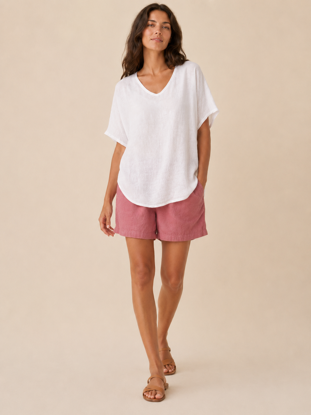 Women’s loose V-neck white top with short wide sleeves and a slightly curved hem.