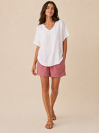 Women’s loose V-neck white top with short wide sleeves and a slightly curved hem.