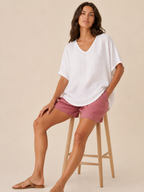 Women’s loose V-neck white top with short wide sleeves and soft, linen-like texture.