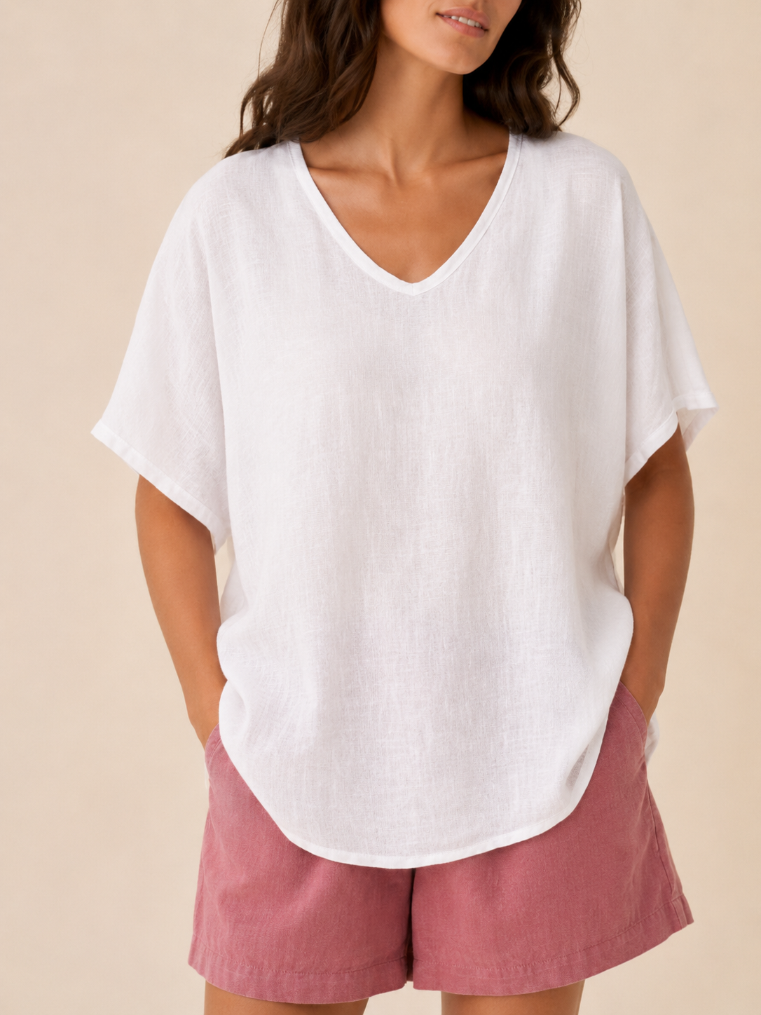 Women’s white loose V-neck top detail, short wide sleeves and subtle fabric texture.