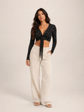 Black long-sleeve crop top with V-neck and front tie, small allover ditsy print