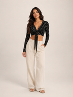 Black long-sleeve crop top with V-neck and front tie, small allover ditsy print