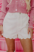 White high-waist denim shorts with scalloped hem and button front