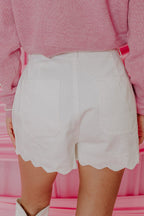 White high-waist denim shorts, scalloped hem, patch pockets, button front