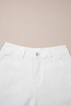 White high-waist denim shorts close-up: button fly and belt loops