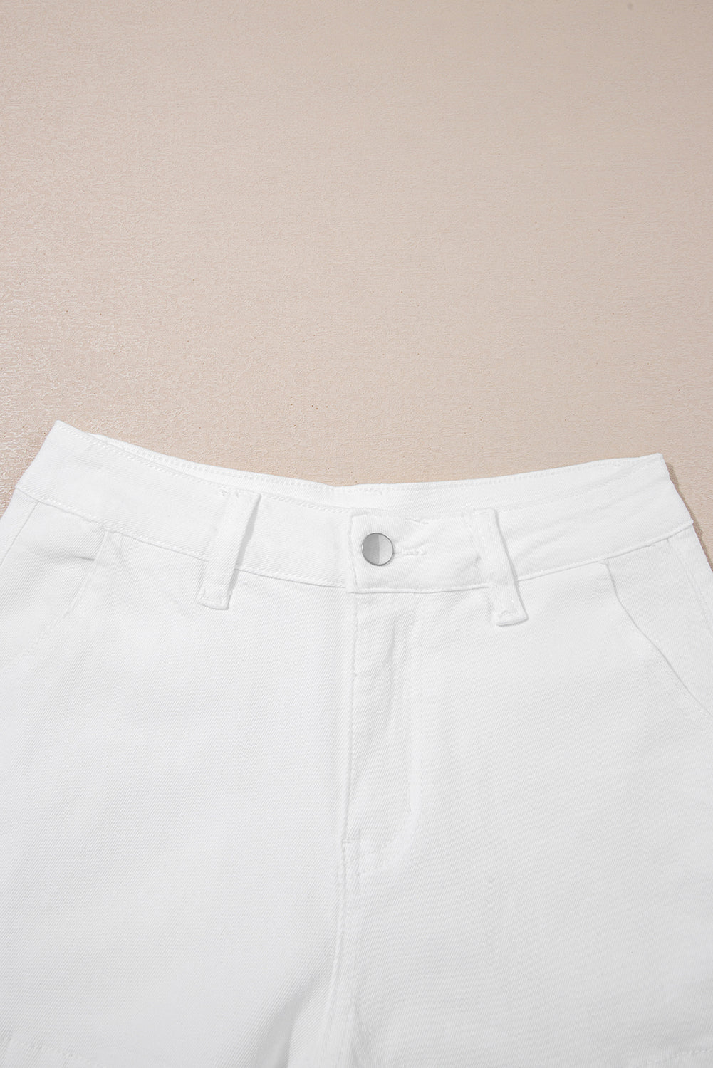 White high-waist denim shorts close-up: button fly and belt loops