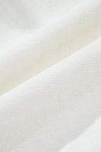 White denim fabric close-up showing fine woven texture and subtle surface grain.