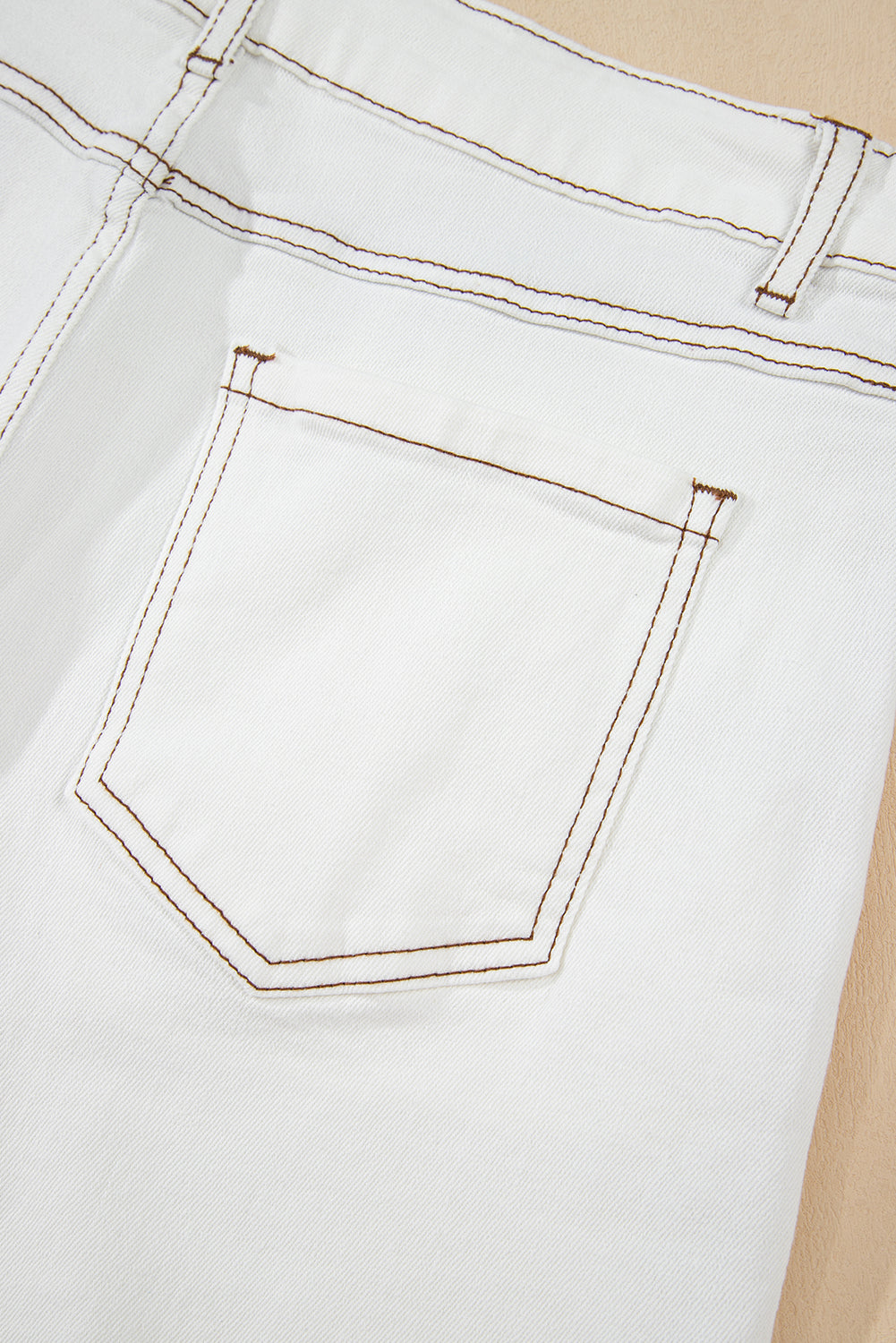 White denim shorts front pocket detail with contrast orange stitching and topstitching.