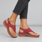 Red toe-post thong sandals on model with textured straps and wedge sole