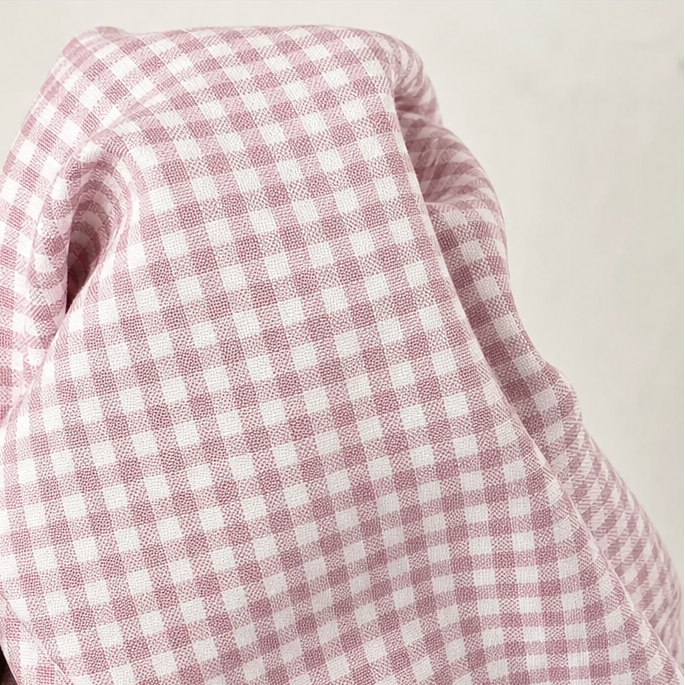 Pink and white gingham fabric close-up with soft drape