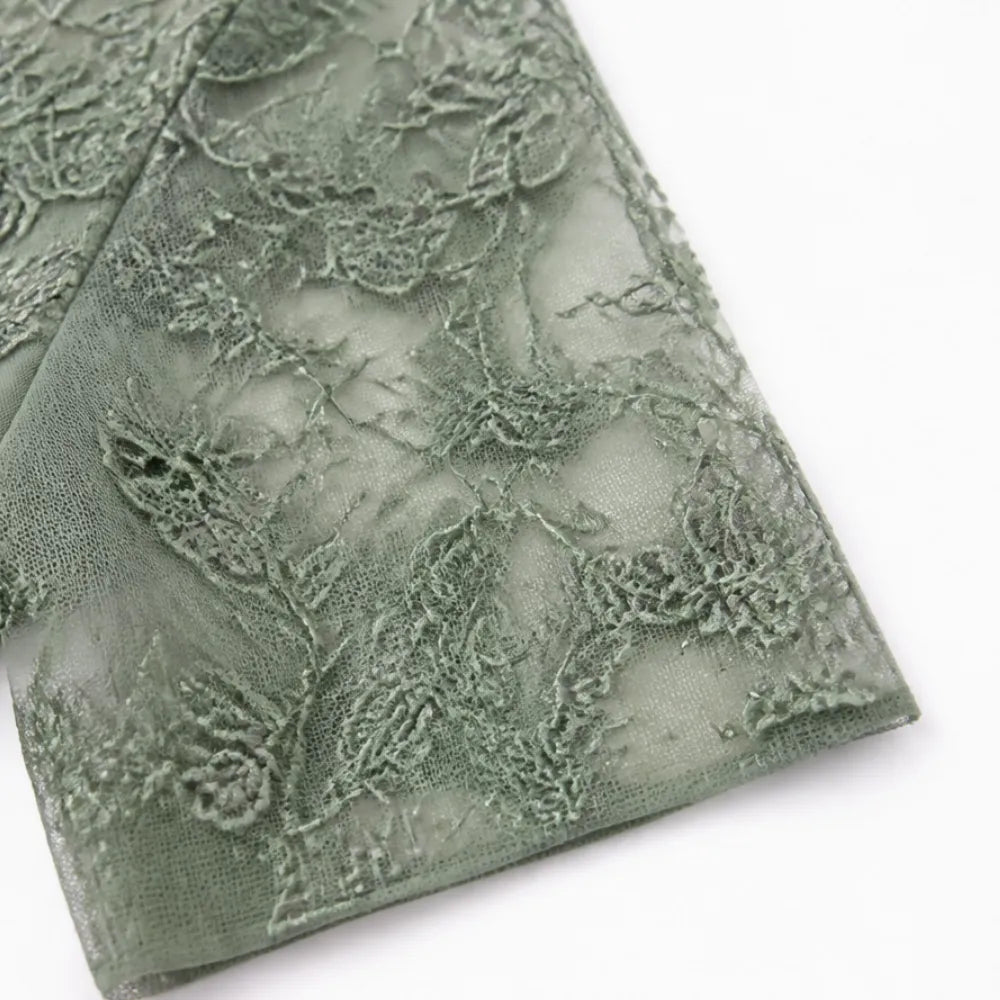 Sage green lace fabric panel with floral embroidery, laid over bodice