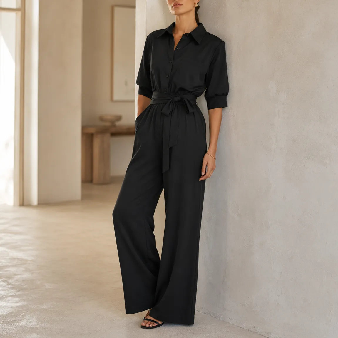 Black belted wide-leg shirt jumpsuit with tie waist and three-quarter button cuffs