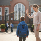 Kids GPS tracker with child wearing a blue backpack in front of a school gate