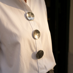 White blouse front with oversized silver buttons on a button placket